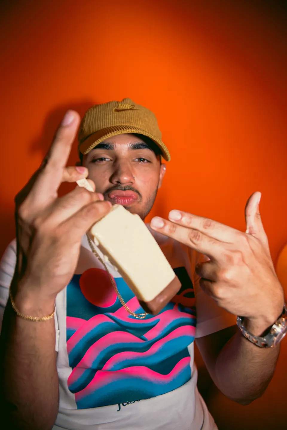 Cliente con actitud mostrando una paleta cremosa IKE frente a una pared naranja